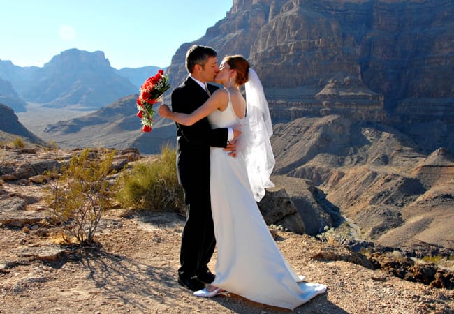 Bride and groom kiss in celebration of their marriage with a the Grand Canyon in the background