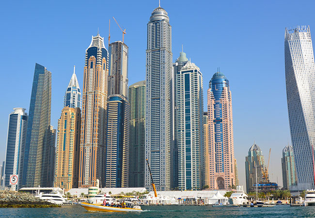 Tour boat cruises through water past skyscrapers in Dubai