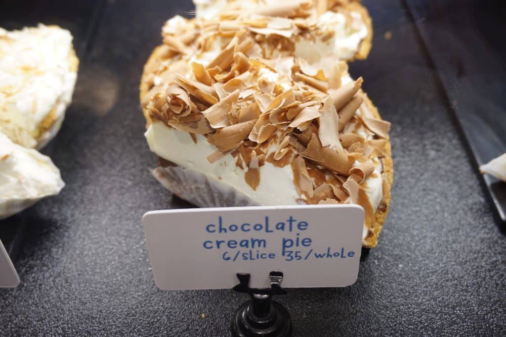 A big slice of chocolate cream pie with a sign next to it at Flour Bakery, a cheap place to eat in Boston.