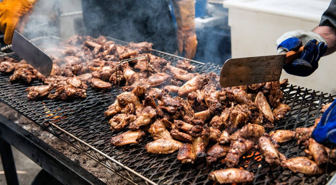 Hot chicken grilling over fire during the Nashville Hot Chicken Festival